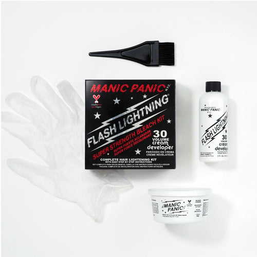 Manic Panic Flash Lighting kit laid out on a white background, including a black applicator brush, a black retail box, a clear protective glove, a white developer bottle, and a white cream container.