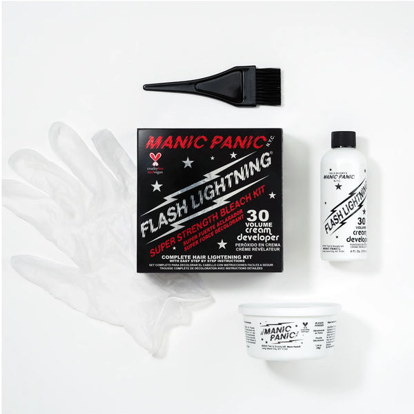 Manic Panic Flash Lighting kit laid out on a white background, including a black applicator brush, a black retail box, a clear protective glove, a white developer bottle, and a white cream container.