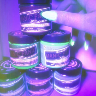 Multiple jars of a product with visible labels, held by a hand under UV light.